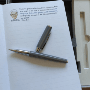 Open Notebook of Wisdom page with an investing quote and a pen